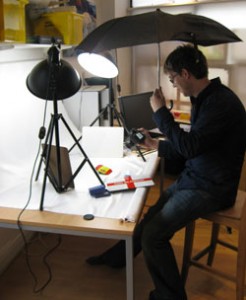 Man holding umbrella for photographing at a table