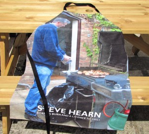 Barbeque apron Man next to barbeque on an apron lying on a table