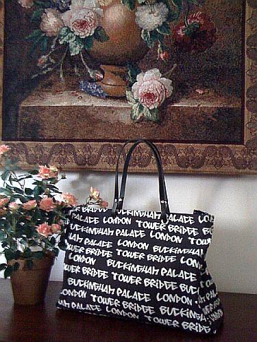 Black handbag with white graffiti words on a table next to flowers and painting