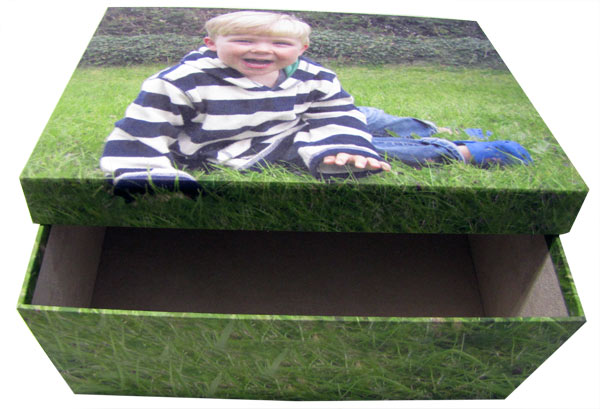 child-photo-box-open Child lying on the grass on an open photo box
