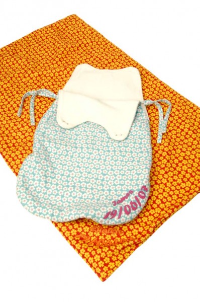 Orange blanket and a blue baby sleeping bag with pink text