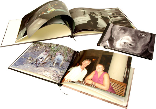 Two open and one closed photo books displaying photos