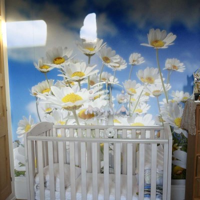 White flowers on photo wallpaper next to a baby crib